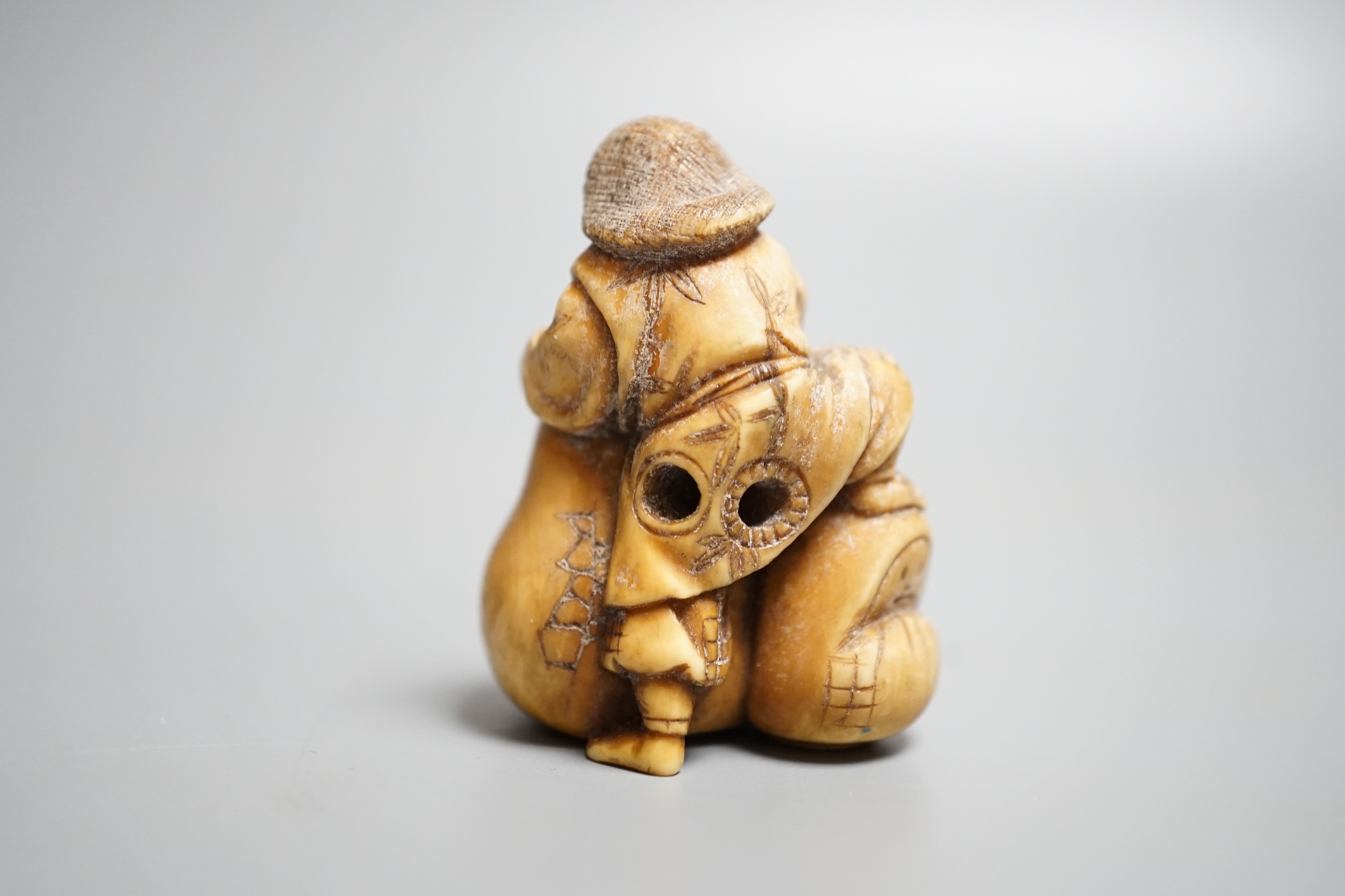 A Japanese ivory netsuke of an artisan and apprentice painting a Daruma doll, early 20th century,height 4cm